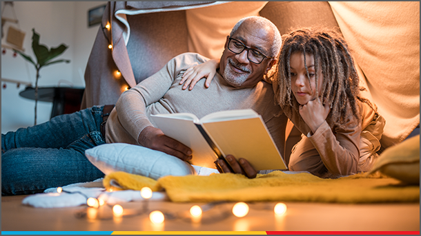 Grandfather and grandson indoor camping reading a book